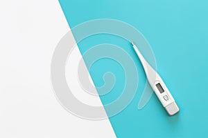 Electronic thermometer on a colored background, flat lay.