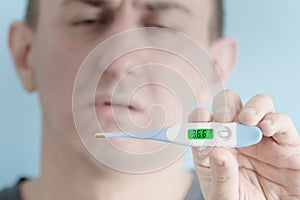 Electronic thermometer in a man`s hand. Man feigning illness in