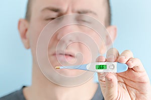 Electronic thermometer in a man`s hand. Man feigning illness in