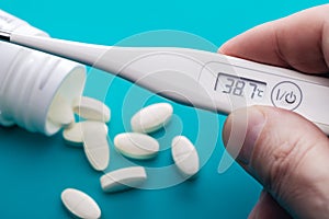 Electronic thermometer in  man`s hand and medications.