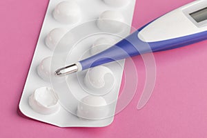 Electronic thermometer and packaging of tablets on a pink background