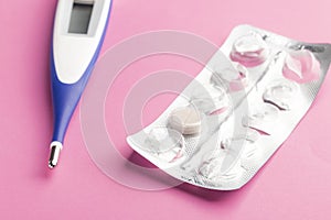 Electronic thermometer and packaging of tablets on a pink background