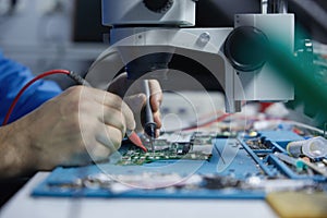 Electronics repair technician working under microscope