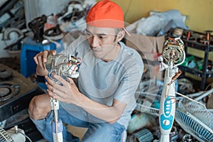 Electronics repairman fixes a broken fan dynamo