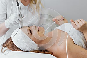 Electroporation without injection mesotherapy. Woman cosmetologist performs cosmetic procedure