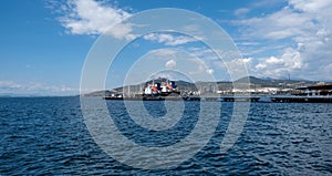 Elefsina Attica Greece. Moored ship at harbor in rippled sea opposite Petroleum Oil Refinery