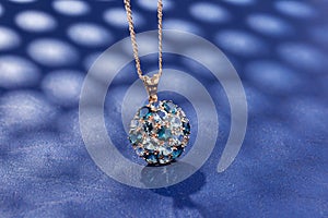 Elegance gold pendant necklace with blue topaz gemstones on blue background