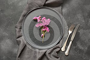 Elegance place setting with pink wildflowers on black table. Top view.