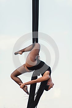 Elegance young beautiful woman dance with aerial silk on a sky background. Fly yoga sport