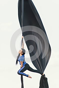 Elegance young beautiful woman dance with aerial silk on a sky background. Fly yoga sport