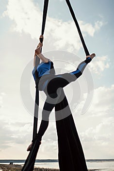 Elegance young beautiful woman dance with aerial silk on a sky background. Fly yoga sport