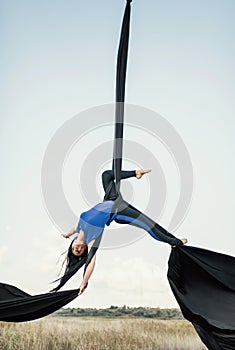 Elegance young beautiful woman dance with aerial silk on a sky background. Fly yoga sport