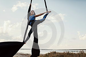 Elegance young beautiful woman dance with aerial silk on a sky background. Fly yoga sport