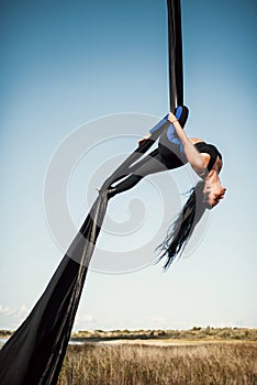 Elegance young beautiful woman dance with aerial silk on a sky background. Fly yoga sport