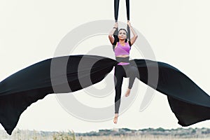 Elegance young beautiful woman dance with aerial silk on a sky background. Fly yoga sport