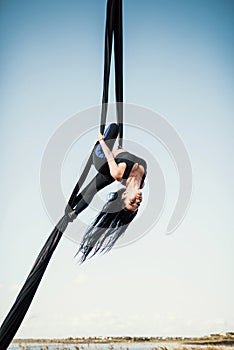 Elegance young beautiful woman dance with aerial silk on a sky background. Fly yoga sport