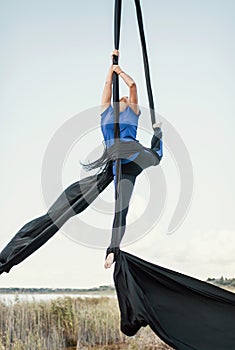 Elegance young beautiful woman dance with aerial silk on a sky background. Fly yoga sport