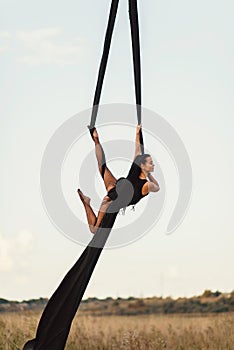 Elegance young beautiful woman dance with aerial silk on a sky background. Fly yoga sport