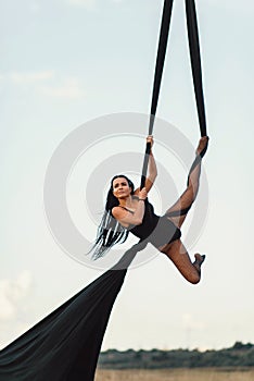 Elegance young beautiful woman dance with aerial silk on a sky background. Fly yoga sport