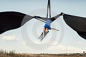 Elegance young beautiful woman dance with aerial silk on a sky background. Fly yoga sport