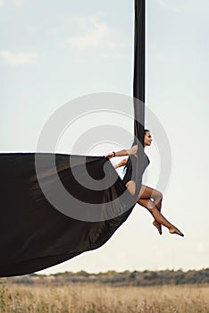 Elegance young beautiful woman dance with aerial silk on a sky background. Fly yoga sport