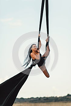 Elegance young beautiful woman dance with aerial silk on a sky background. Fly yoga sport