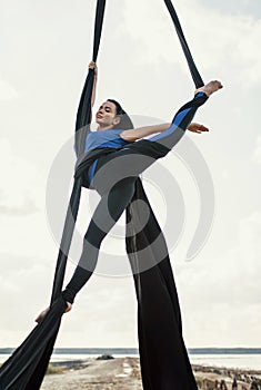 Elegance young beautiful woman dance with aerial silk on a sky background. Fly yoga sport