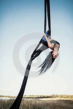 Elegance young beautiful woman dance with aerial silk on a sky background. Fly yoga sport