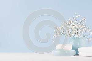 Elegant accessories for dressing table - soft pastel blue ceramic bowls, white flowers, products for skin and body care on white.