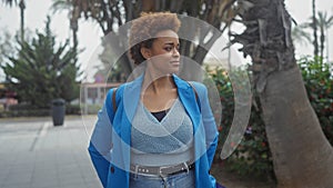 An elegant african-american woman in a blue blazer enjoys a stroll in a lush garden setting photo