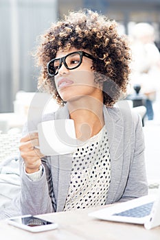 Elegant african american woman drinking coffee, working.