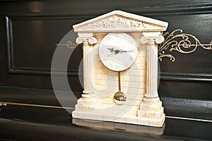 Elegant antique clock. Clock with Greek temple. Marble clock on black piano