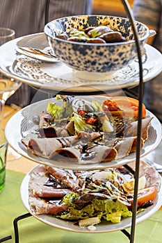 Elegant appetizer presentation on a three tiered serving stand, featuring roast beef, ham, salad, and mushrooms photo