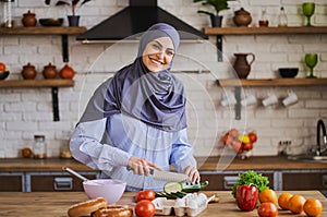 Elegant Arabian woman cooking a meal in her kitchen and smiling to the camera