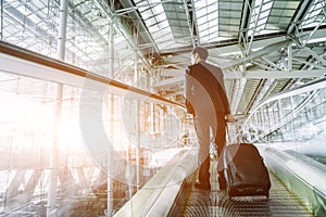 Elegant asian businessman checking email on mobile phone while walking with suitcase inside airport