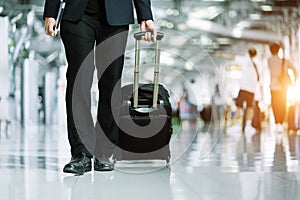 Elegant asian businessman checking email on mobile phone while walking with suitcase inside airport