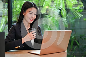 Elegant Asian businesswoman remote working in the office shop, using laptop