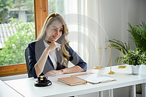 Elegant Asian female lawyer or business legal consultant sits at her office desk