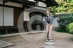 An elegant asian photographer walking out joyfully