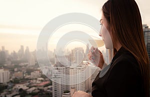 Elegant Asian woman drinking cocktail at rooftop bar