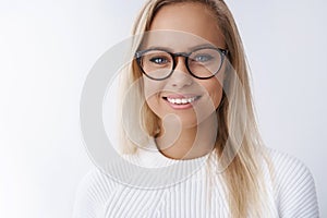 Elegant attractive young businesswoman in glasses smiling delighted, satisfied with new frame of eyewear gazing friendly