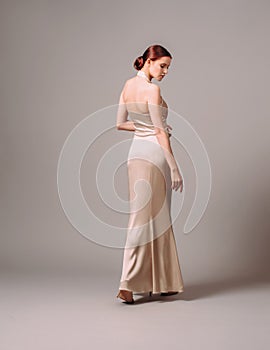 Elegant backless moscato dress. Beautiful ivory silk evening gown. Studio portrait of young ginger woman. Transformer dress idea f