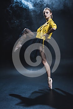 elegant ballerina in pointe shoes and black tutu and yellow leather