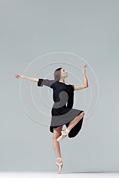 Elegant ballerina. A young graceful ballet dancer, dressed in pointes shoes demonstrates her dance skills. Power and refinement of