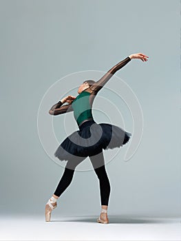 Elegant ballerina. A young graceful ballet dancer, dressed in pointes shoes demonstrates her dance skills. Power and refinement of