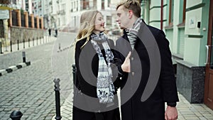 Elegant beautiful blonde couple walking city street, looking at each other with smile and kissing