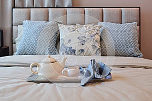 Elegant bedroom interior with floral pattern pillow and decorative tea set