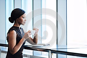 Elegant black female looking out window with her morning tea