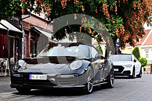 elegant black German made luxury sports car parked along old urban sidewalk. sidewalk cafe. European city.