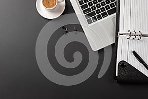 Elegant black office desktop with laptop and cup of coffee. Top view